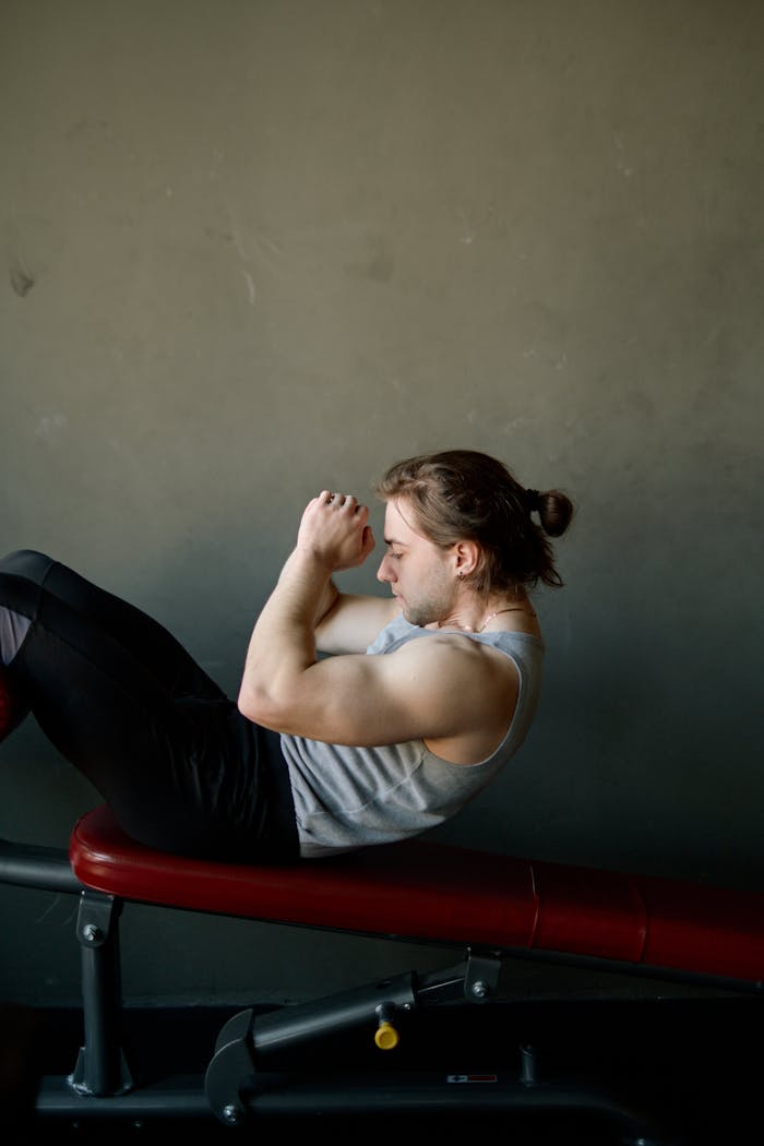 Man performing a workout on a bench in a gym, showcasing effort and strength.